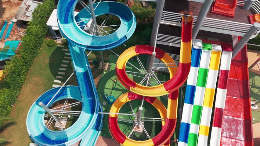 Colorful water slides attracting tourists of mixed ages, providing exciting recreation and refreshing summer enjoyment at vibrant aquatic resort destination