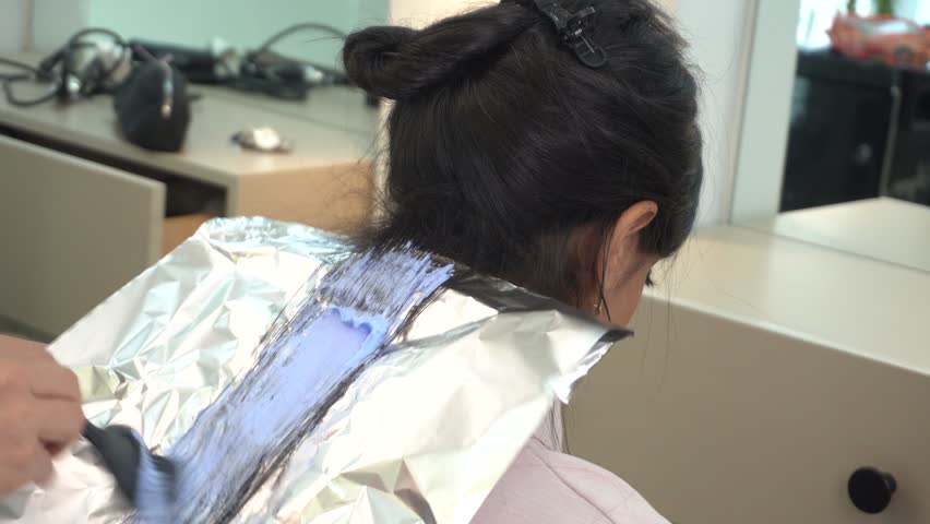 Female hair decolorizing in salon. Blue Plex hair bleach