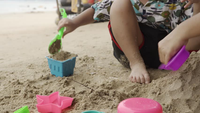 Children happily build sandcastles on the beach under the warm sunlight, creating joyful holiday memories with family and friends. 4k video footage