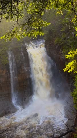 Miners Falls at Pictured Rocks National Lakeshore in Michigan during sunrise with cascading water and glowing forest scenery.