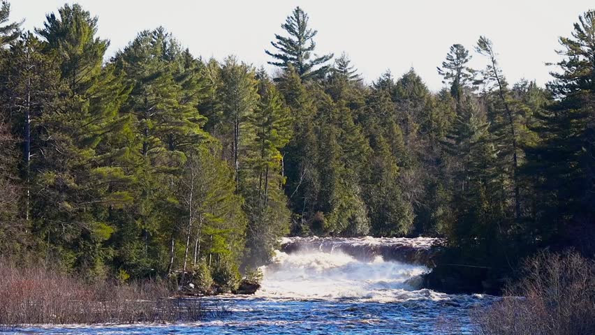 Tahquamenon Lower Falls in Michigan with multiple cascades and forest backdrop at sunset