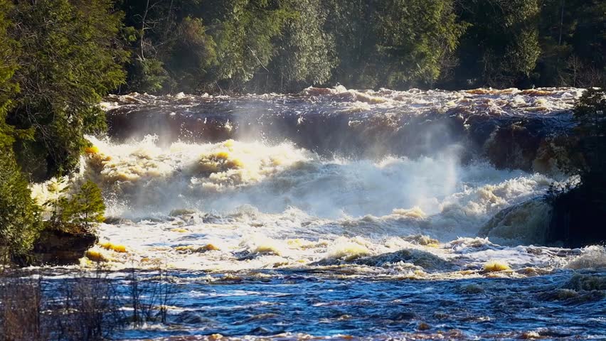 Tahquamenon Lower Falls in Michigan with multiple cascades and forest backdrop at sunset