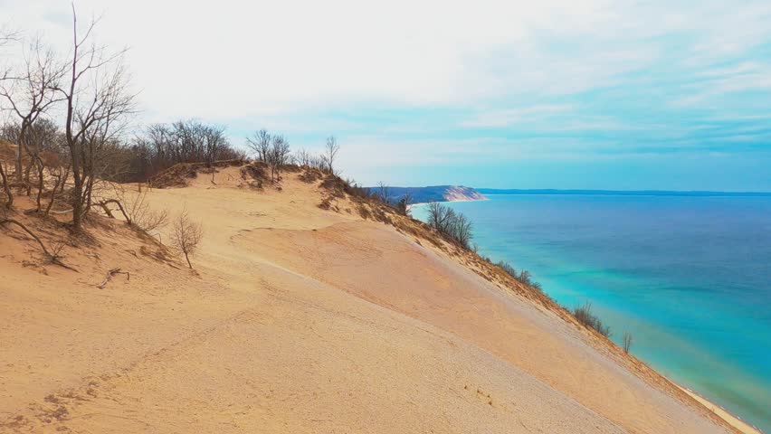 Breathtaking Sleeping Bear Dunes along Lake Michigan on a sunny summer day. The sweeping sandy dunes, turquoise water, and lush shoreline represent the natural beauty and adventure of Norther