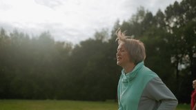 Sport woman jogging energetically across open field, panting with joyful smile, hair flying in wind under bright sky, wearing athletic hoodie, radiating happiness and vitality - Powered by Shutterstock - Get 15% off with code: PIKWIZARD15