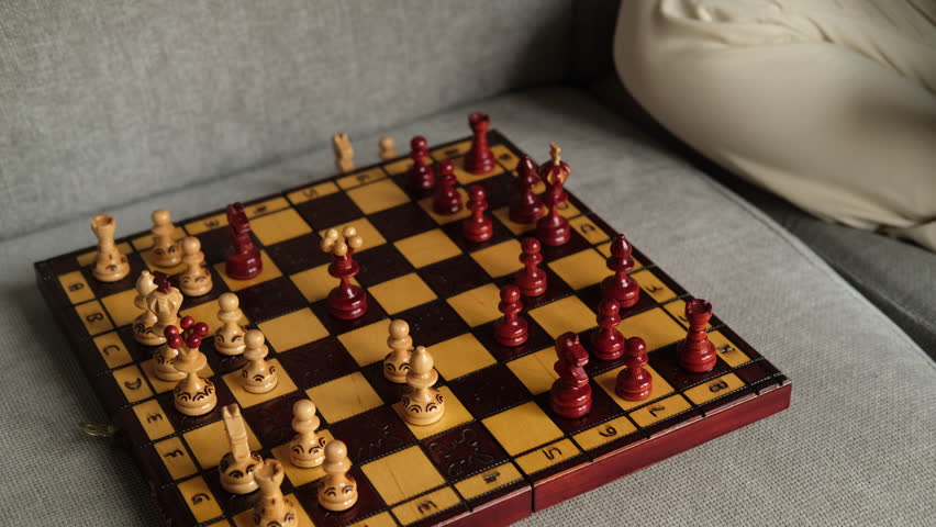 A woman is playing chess and moving chess pieces around the board