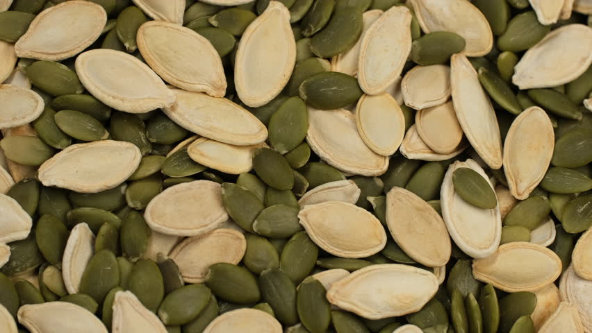 Mixed pumpkin seeds and peeled pumpkin seeds top view, rotation