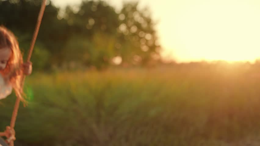 Cute girl child smiles plays on swing, dreams. Child swings on tree on swing. Child