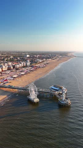 Vertical aerial view of the sunset on the beach in The Hague, Netherlands. The North Sea coast, Scheveningen Pier and the famous Ferris wheel SkyView de Pier.