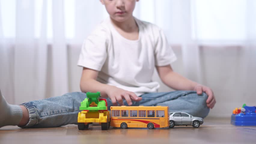Young boy playing with toy cars. Child plays with a toy car. A boy is playing with toys in a car at home. A little boy engaged lifestyle in play with toy vehicles.