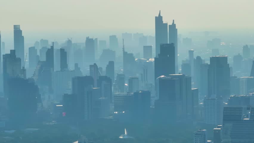 Rising haze envelops a bustling city skyline as air pollution impacts daily life and visibility at dusk