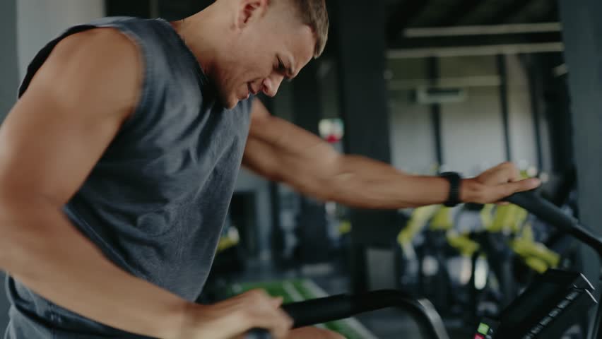 Focused shot of an individual pedaling a stationary bike inside a gym. Concept of fitness, exercise motivation, and health lifestyle. Person Exercising on Stationary Bike in Gym Environment