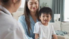 Asian Doctor Checks Sick Childs Temperature with Thermometer as Mother Comforts Him at Home, Highlighting Family Healthcare and Medical Care for Unwell Kids - Powered by Shutterstock - Get 15% off with code: PIKWIZARD15