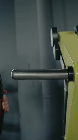 Athletic man working out on a chest press machine in the gym. He is focused and determined. Focused Man Exercising on Chest Press Machine at the Gym. Man Exercising on Machine in Gym. Vertical