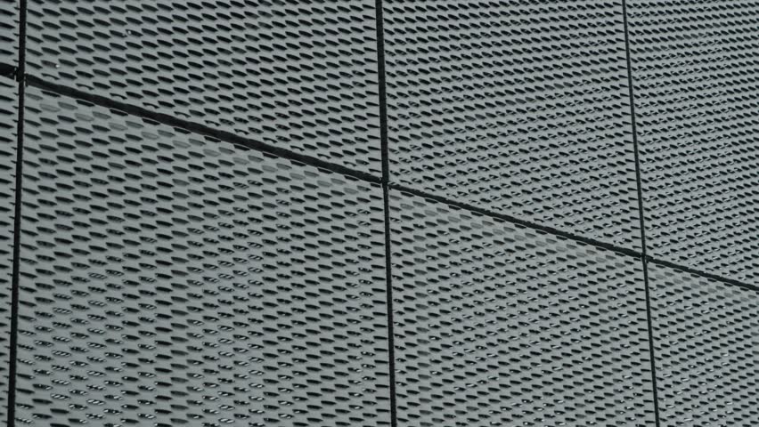Close-up of a modern building facade with expanded metal mesh. The metal grid creates a textured and patterned surface. Ideal for architectural, design, or abstract backgrounds.