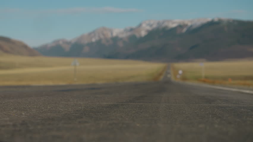 Close up of female legs walking on empty rural road. Woman moving forward and fading into soft focus, symbol of journey, freedom and life path.