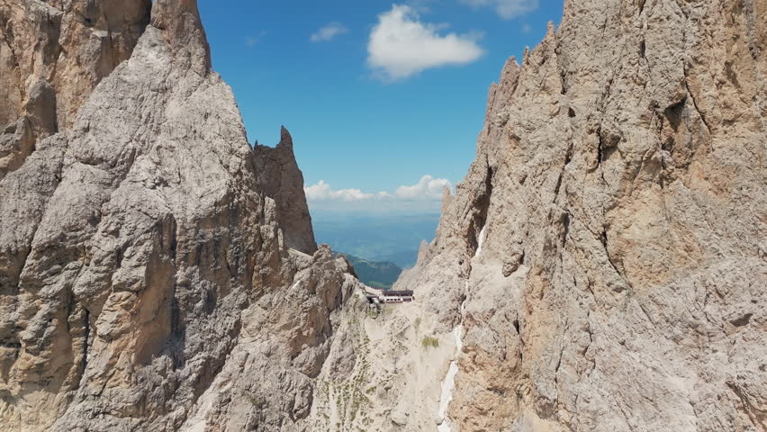 Slow panning drone shot of Toni Demetz Hut perched dramatically in the Forcella del Sassolungo, Dolomites, Italy