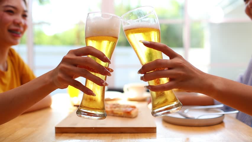 A young bartender pours a fresh beer into a glass at a shiny metal bar, capturing motion, craftsmanship, and the energy of a modern pub setting.

