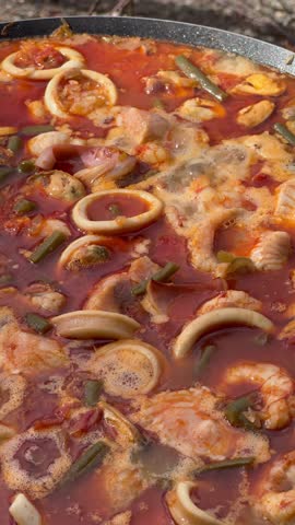 Spicy seafood stew with squid, shrimp, and vegetables boiling in a pot