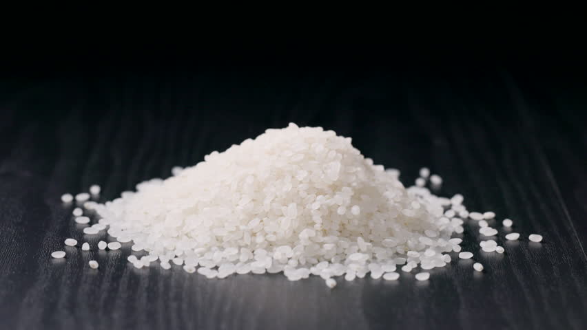 Pouring Japanese Raw Rice onto a Black Background