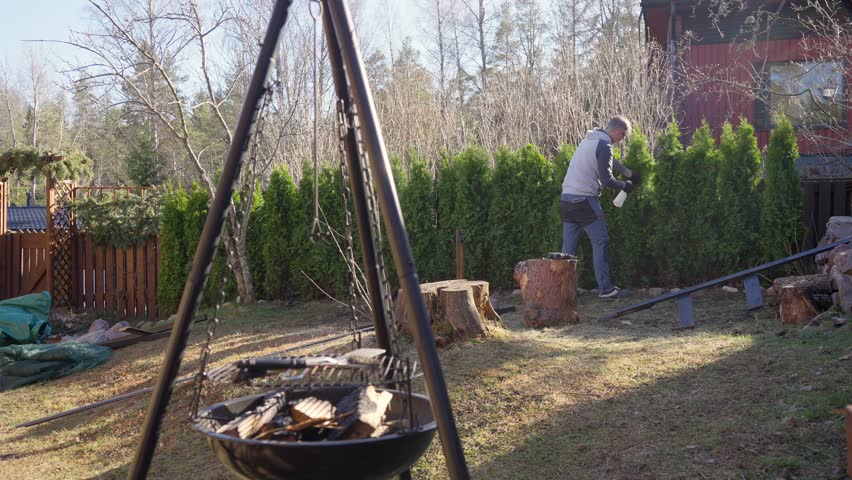 Man spraying evergreen bushes hedge in backyard garden with a spray bottle. Outdoor gardening work on a sunny spring day. Pest control caring for garden plants