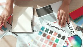 Top view slow motion hand closeup on table of two designer choose color for graphic design working or client seeking color application at creative chromatic consultation from designer. Variegated - Powered by Shutterstock - Get 15% off with code: PIKWIZARD15