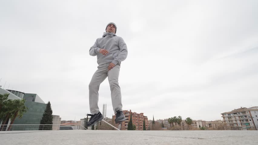 Breakdancing performer executing dynamic power moves and freeze techniques against urban cityscape backdrop, displaying skill and artistic expression