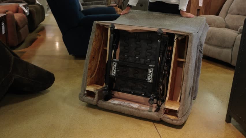 Person inches flipped recliner toward lens, revealing its full underside mechanism