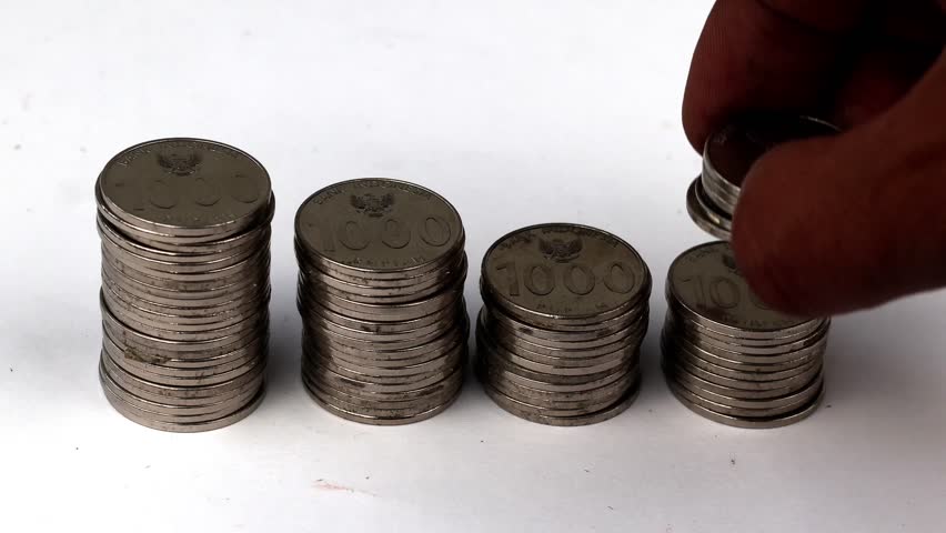 Hand stacking coin with different heights, Saving money concept preset by Male hand putting money coin stack growing business, young man stacking coins on white table.
