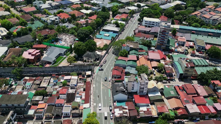 Aerial flyover of residential house rooftops along busy streets of Col. Bonny Serrano Avenue, Quezon City, Philippines