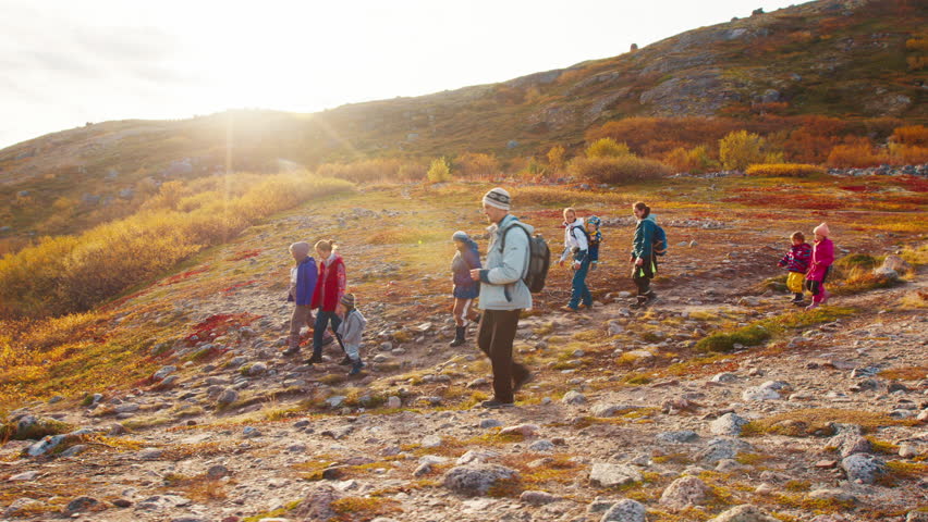 Hikers with kids walk on the trail in the Arctic tundra