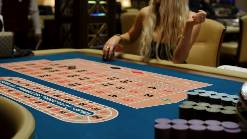 Casino Roulette Table with Dealer Arranging Bets and Chips in Action