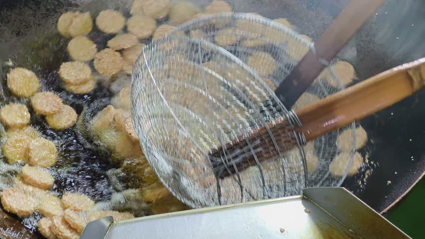 Close-up process of frying crispy rice crackers in the hot oil and frying pan.