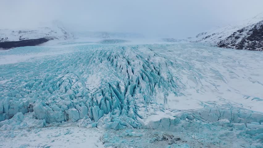 Aerial view of majestic icy blue glaciers in Iceland. Above view of Glacier skaftafell, Vatnajokull National Park, Jokulsarlon Glacier lagoon. FPV drone flying around snow-covered ice cliffs Greenland