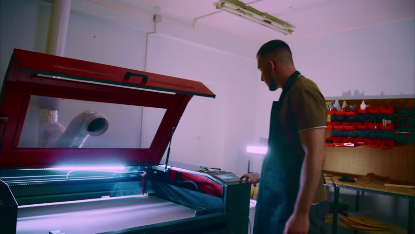 Skilled craftsman works on a laser engraving machine, meticulously controlling the process with precision and expertise in a dedicated workshop environment