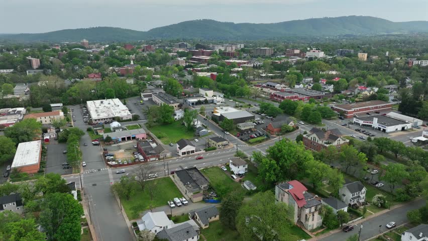 Cars on street on junction of american town at cloudy day. Aerial view. Charlottesville, Virginia. Aerial wide shot. Cloudy day in spring. City center with mountains in distance.