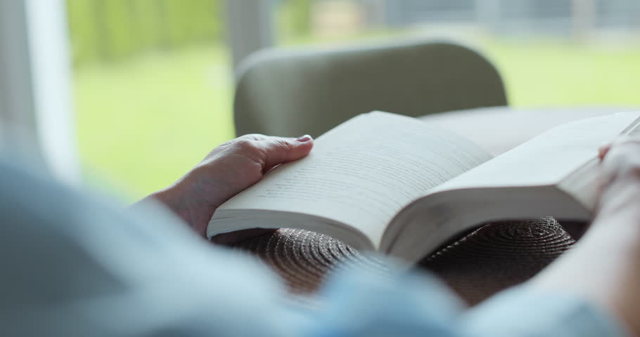 Close-up of female hands turning page book. Woman reading book.