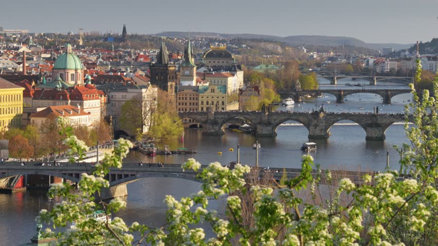 Scenic view of Charles Bridge and Vltava River in Prague during spring with blooming flowers and vibrant city life. Panoramic shot of Prague city center, Czech Republic 