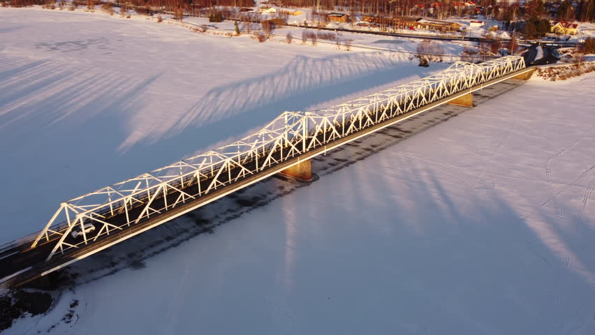 Aerial following snowy bridge over frozen river, Tornio, Finland