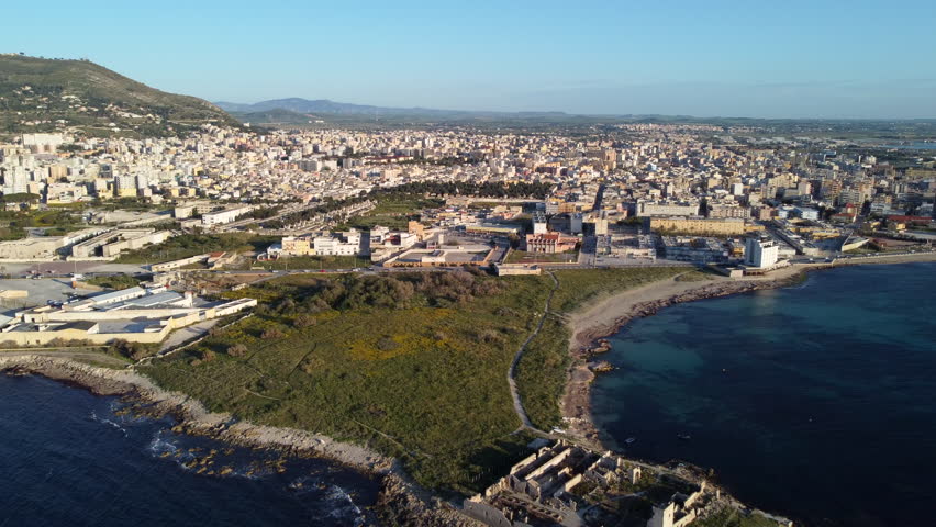 City Of Trapani In Sicily, Italy, With Ruins Of Tonnara San Giuliano On Rocky Peninsula In Foreground. aerial pullback shot