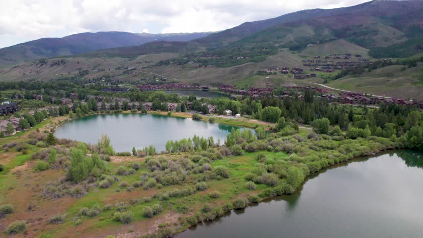 Aerial video of ponds near Silverthorne, Colorado. Camera flies over a pond with houses in the background.