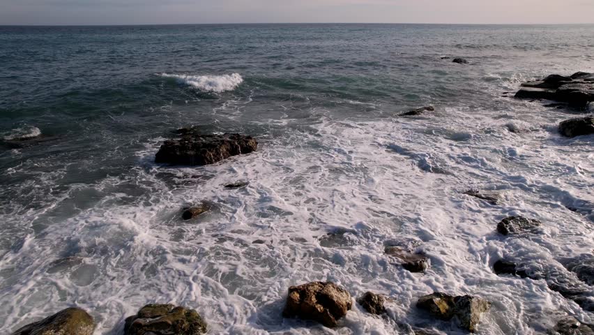 Experience tranquility of sea with this stunning drone footage, featuring waves rhythmically colliding with majestic rocks. For enhancing travel content, nature films, serene visual storytelling.