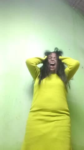 The expression of a woman experiencing depression, frantically messing with her hair while screaming hysterically.
