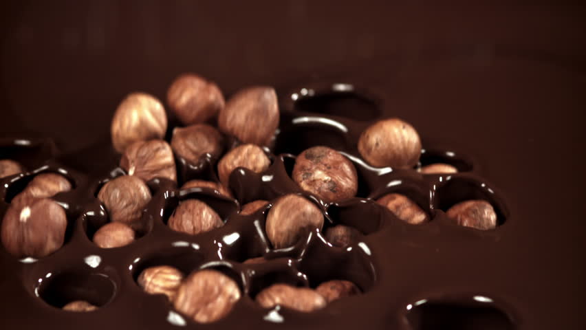The hazelnuts fall into the liquid chocolate. Filmed on a high-speed camera at 1000 fps. High quality FullHD footage