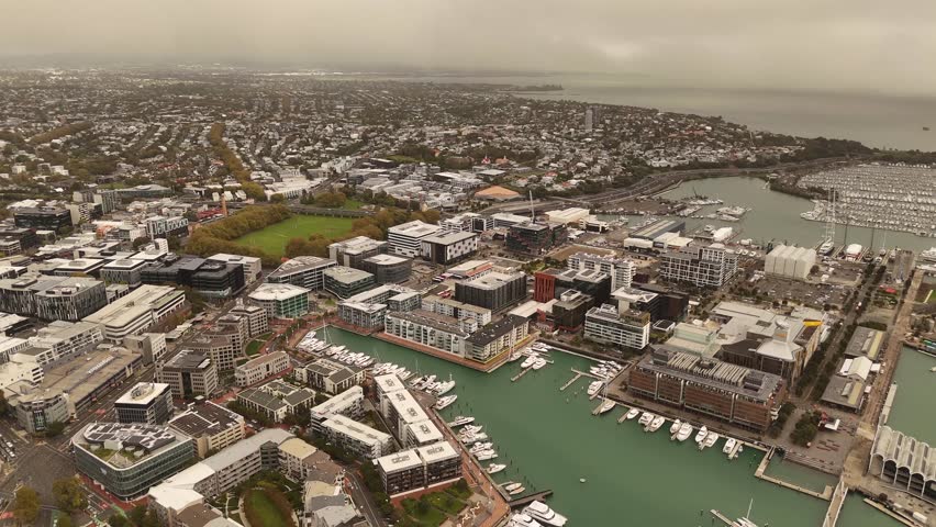 Viaduct Harbour of Auckland city, Wynyard Quarter, and Westhaven Marina, buildings, numerous boats, cloudy sky, New Zealand. Aerial drone panoramic view