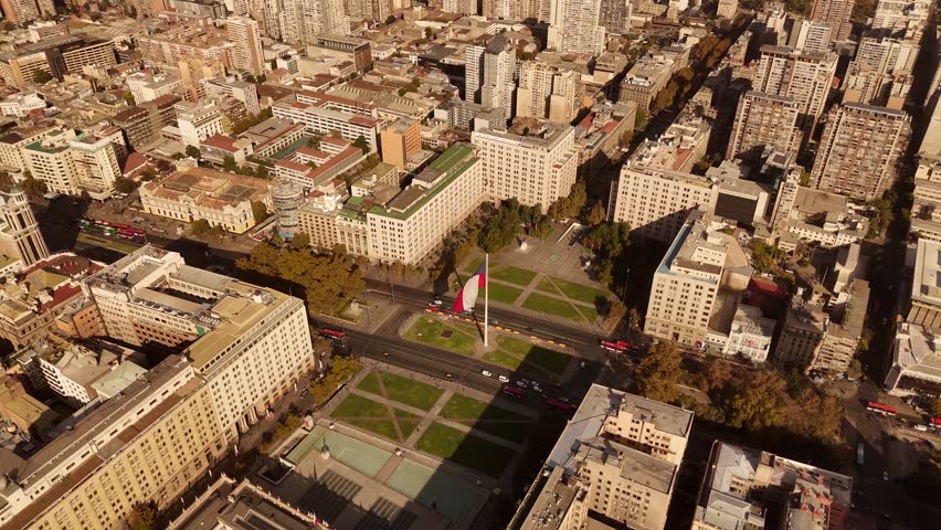 Sunset time in de Chile with traffic on main street. Waving american flag in center of city. Aerial view. Apartment blocks and residential area in downtown.