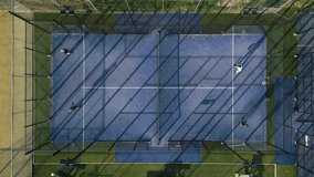Drone footage showing a top-down view of a blue padel court with players, surrounded by trees and morning shadows. Perfect for sports and urban lifestyle themes. - Powered by Shutterstock - Get 15% off with code: PIKWIZARD15