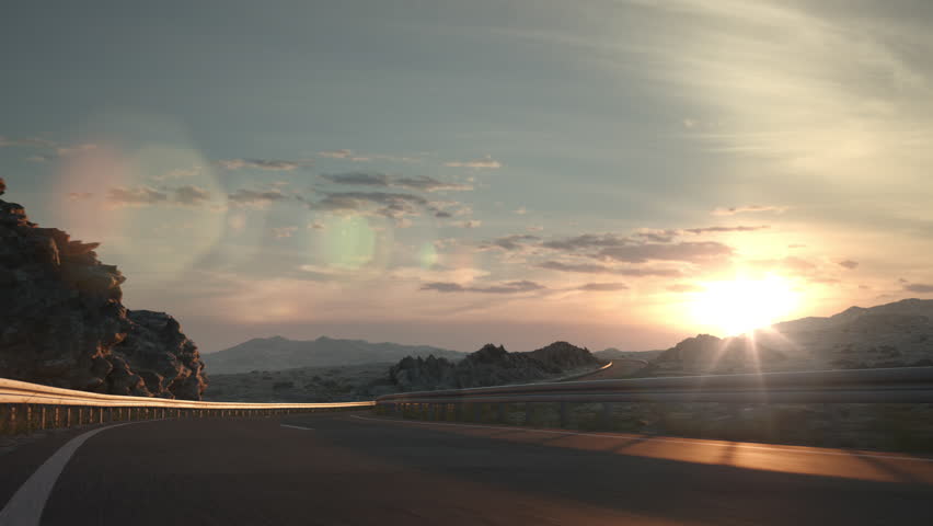 A long distance semi truck with cargo trailer passes the camera driving on a desert road into the sunset. Low angle camera. 3d animation rendering.