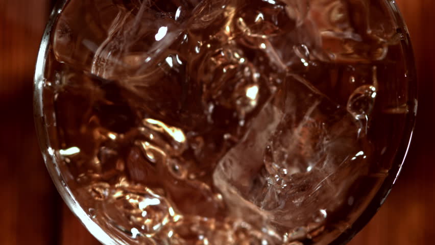 Ice falls into a glass of whiskey. Filmed on a high-speed camera at 1000 fps. High quality FullHD footage