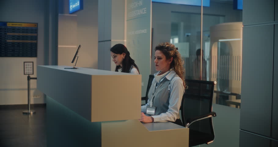 International Airport Terminal: Young Male Passenger Placing Suitcase near Counter for Baggage Check-in before Boarding Flight, Talking to Female Airline Agent. Security Checkpoint in the Background.