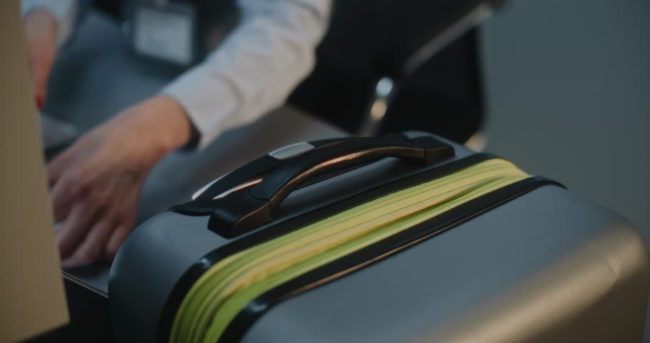 Airport Check-in Counter: Close Up of Female Airline Worker Putting Luggage Tag Sticker on Suitcase for Boarding Flight. Customer Service and Security Baggage Check in International Airport Terminal.